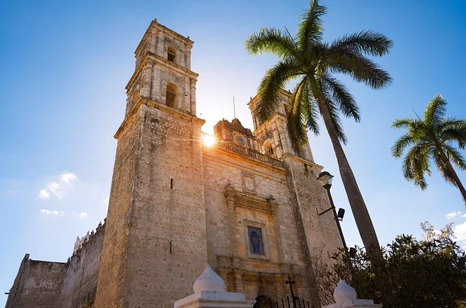 The stone facade of Valladolid cathedral at sunset with palm trees