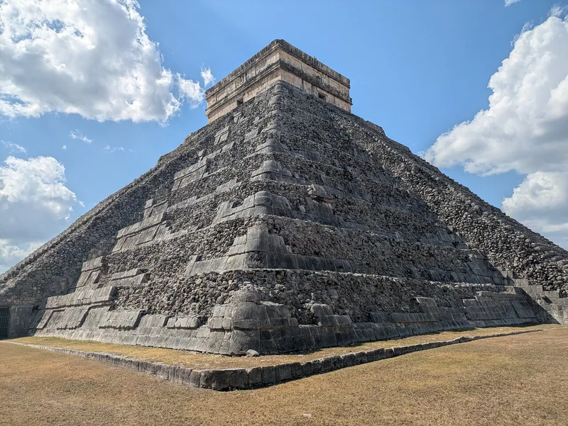 El Castillo pyramid at Chichen Itza under a blue sky with clouds