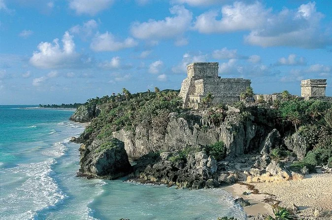 Tulum's El Castillo temple on a rocky cliff above turquoise water and a strip of beach